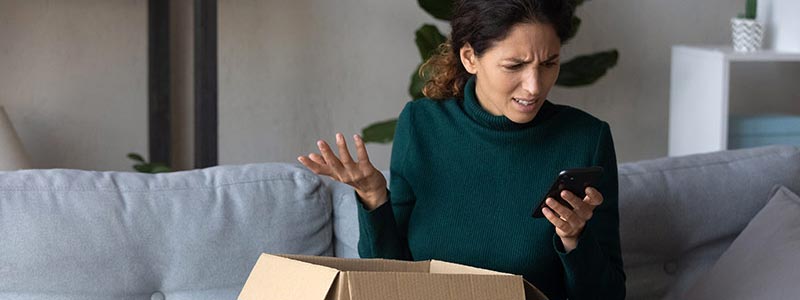 Woman opening a package looking confused at her phone