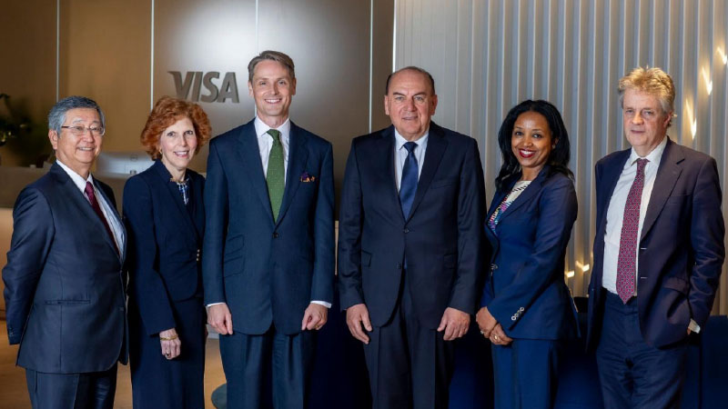 The six members of the Visa Economic Empowerment Institute's advisory council pose together in front of a Visa logo.